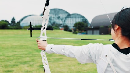 Woman, archery and aim arrow in training at academy, outdoor exercise and practice skill. Female person, shooting challenge and field for competition games, learning and practice with tool in japan