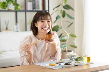 朝食でお味噌汁を飲む若い女性