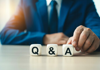 A businessman arranging three cubes labeled "Q&A"