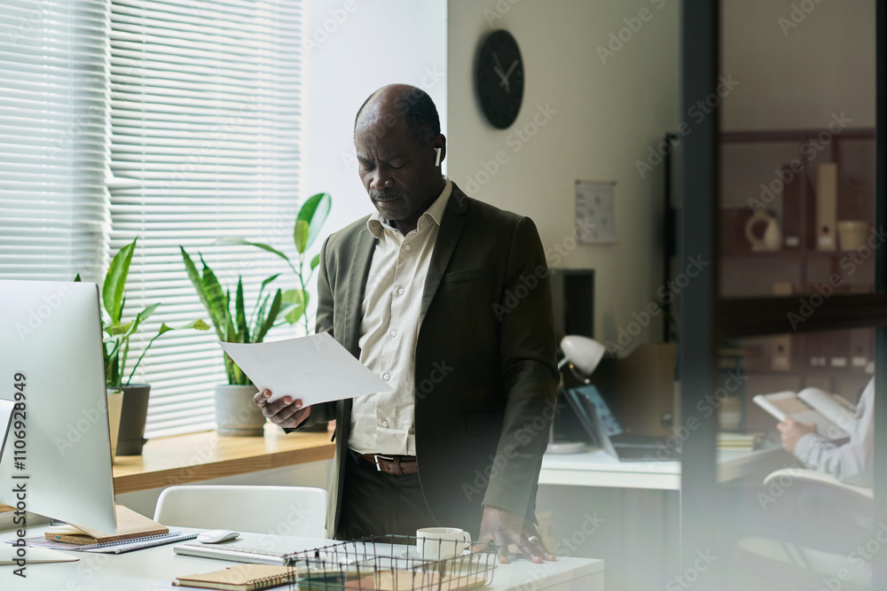 Aufkleber experienced male chief executive officer standing by workplace with desktop computer and looking thr