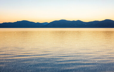 Fototapeta premium Captivating sunrise over a tranquil lake surrounded by mountains