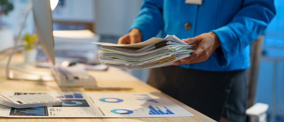 Businesswoman, accountant holding a pile of documents prepared for executives to attend a meeting. Many documents attending a meeting in the company. Clearing work, searching, managing.