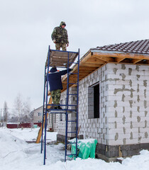 Two men are working on a house, one of them is on a ladder