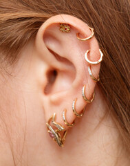 A woman with a variety of earrings, including a gold hoop and a diamond stud