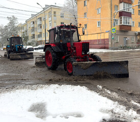 A red tractor is plowing a street
