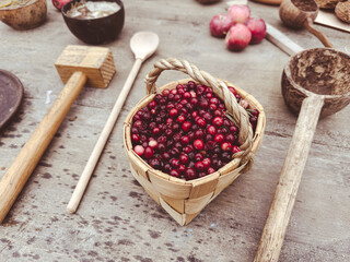 A basket of berries sits on a table next to a wooden spoon and a wooden mallet
