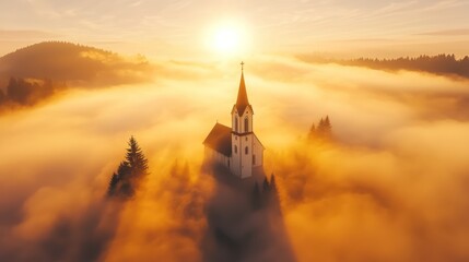 Obraz premium A serene church emerges from mist at sunrise, surrounded by mountains, creating a tranquil and ethereal atmosphere.