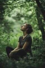 Obraz premium Woman is sitting in the woods, looking up at the sky. She is in a peaceful and contemplative mood