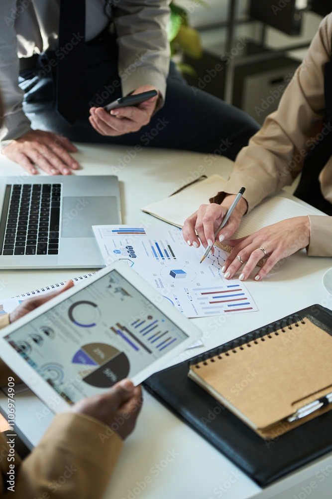 Poster cropped shot of three unrecognizable brokers analyzing financial charts and diagrams at working meet