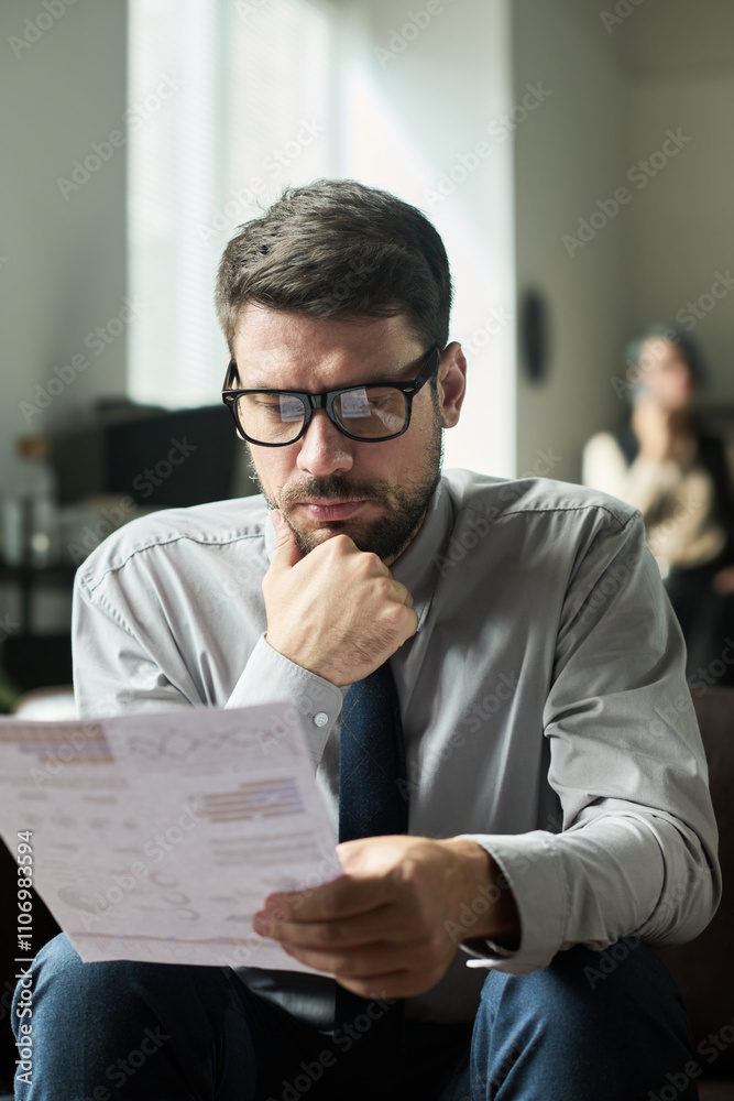 Poster young businessman thinking of market development while looking through financial data in paper docum
