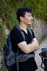 Young photographer observing nature with his hands crossed in the middle of a rocky path in a...