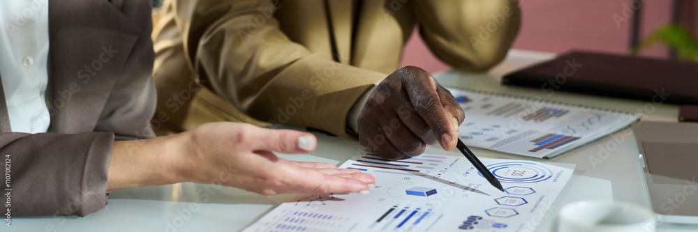 Poster header of hand of mature african american businessman pointing at graphic data on paper document dur