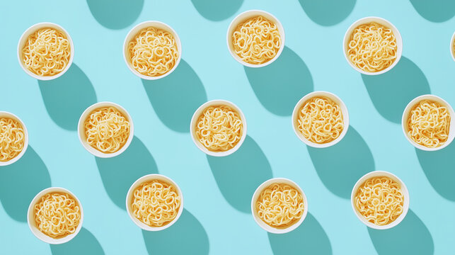 Flat lay of multiple bowls of instant noodles arranged on a pastel blue background