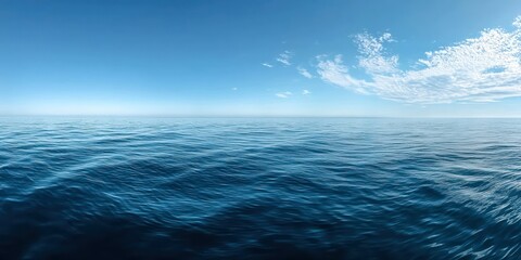 Obraz premium A panoramic view of a tranquil ocean with gentle waves and a clear blue sky, conveying serenity.