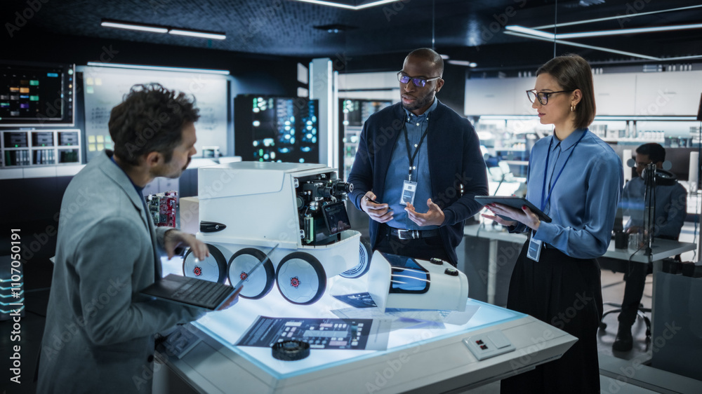 Fototapete Diverse Team of Industrial Specialists Working on Remotely Controlled Robot. Young Male and Female Engineers in a Lab Discussing an Autonomous AI Delivery Assistant Prototype, Brainstorming