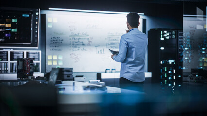 Portrait of a Male Specialist Working in a Technological Startup Taking Notes from the White Board in Office. Professional Data Analyst Collecting Information for Project Development