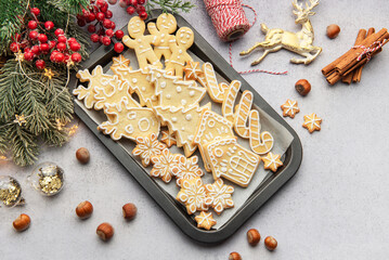 Christmas cookies decorated with icing on baking tray with festive decorations