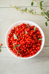 fresh ripe red goji berries in a bowl on a wooden table