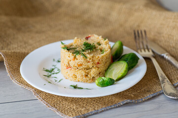 homemade cooked bulgur with Brussel sprouts in a plate, on a wooden table