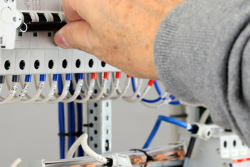 The hand turns on the automatic current switch in the electrical switchboard. Close-up. Soft focus.