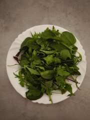 Fresh, vibrant green salad mix on a white plate, promoting healthy eating habits and vegetarian lifestyle