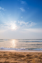 The morning beach by the ocean is empty and the sky is bright blue.