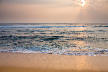 The sun is setting, casting a warm glow over the ocean