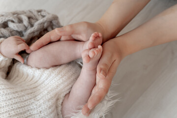 the legs of a newborn baby in mom's arms on a white background or in a crib, a place for text, mom holds the baby in her arms