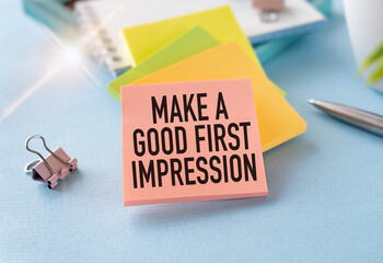 The text Makes a Good First Impression in a notebook on a white desk with office supplies.