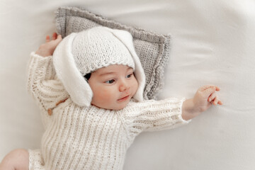 A newborn baby in a bunny hat with ears on a white background with open eyes, a place for text, a young family with a child