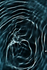 Black water with ripples on the surface. Defocus blurred transparent blue colored clear calm water surface texture with splashes and bubbles. Water waves with shining pattern texture background. 