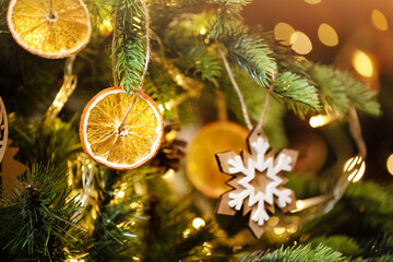 Christmas decoration. Dry slices of orange ornaments and wooden ornaments on christmas tree. Eco Christmas holiday concept. Zero waste, eco friendly. Sustainable christmas.