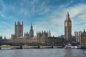Westminster palace with elizabeth tower, also known as big ben, is standing on the bank of the river thames behind westminster bridge on a sunny day with some cirrus clouds in a blue sky