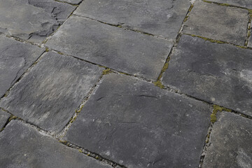 Obraz premium Textured stone pavement, aged gray slabs with mossy edges and visible wear, rustic and tactile
