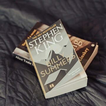 Closeup of Stephen King's Billy Summers novel laying on a dark gray bed sheet