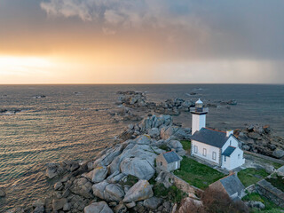 Phare sur un promontoire rocheux  face à la mer au coucher du soleil en vue aerienne. Le phare de...