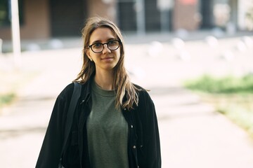 Portrait of a smiling young girl with glasses in the park. High-quality photo