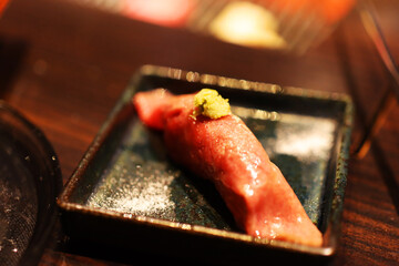 Sushi piece topped with wasabi on a dark plate