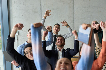 Obraz premium A diverse team of business professionals ecstatically celebrating their success in a modern office, expressing triumph and unity after achieving their goals
