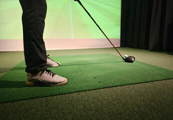 Professional male golfer playing golf indoors in golf simulator closeup