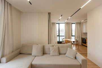 Bright living room interior with large sofa and oak wooden floor. Concept of minimalist design. Comfortable place for meeting.