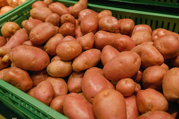 A bountiful display of fresh, red-skinned potatoes fills a green crate in a supermarket, ready for...