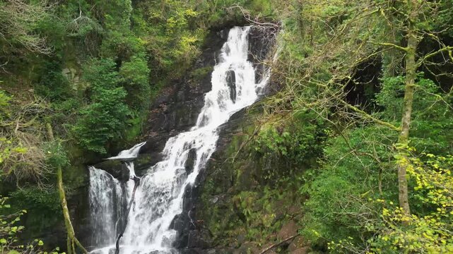 Stream of water cascading in the forest, Torc waterfall drone aerial landing. Autumn in Ireland