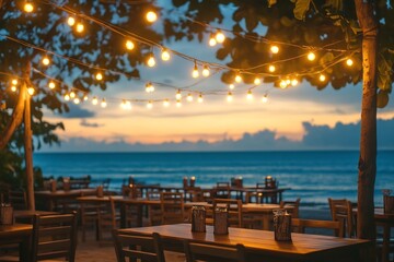 Fototapeta premium Beachside Tables Set Under Glowing String Lights at Sunset