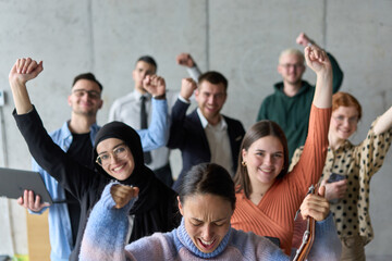 A diverse team of business professionals ecstatically celebrating their success in a modern office, expressing triumph and unity after achieving their goals