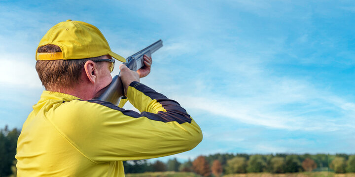 clay pigeon shooting, athlete in yellow uniform prepared to hit clay pigeon
