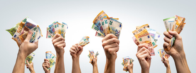 Fototapeta premium Many hands holding Euro banknotes up in the air