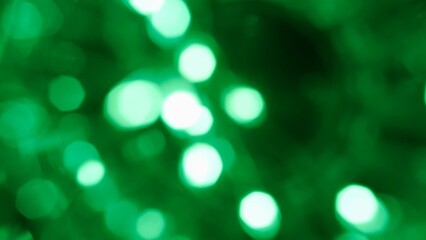Obraz premium Blurred glowing green lens flare motion studio lightning, garland with bokeh effect on dark background. Light leaks shining, abstract background footage.
