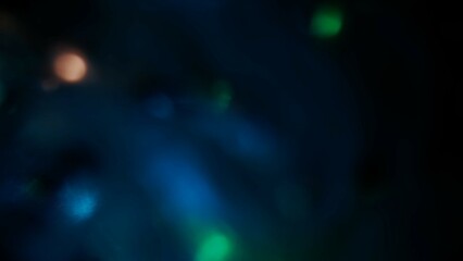 Blurred blue green lens flare motion studio lightning, texture reflection with bokeh effect on dark black background. Light leaks abstract background footage.