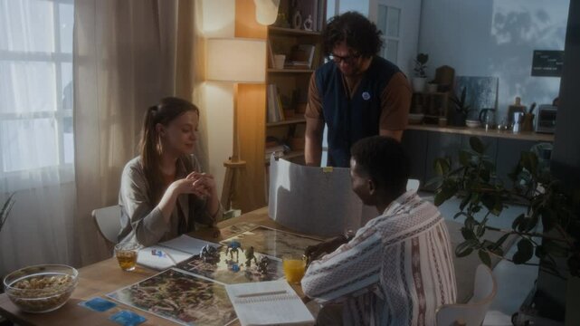 Group of three young friends starting fantasy role-playing board game, young man speaking about rules